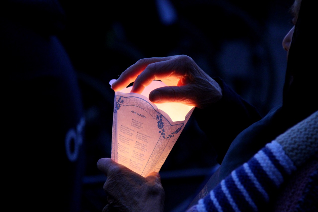 La mano di una fedele illuminata da una fiaccola durante una veglia a Lourdes, in Francia