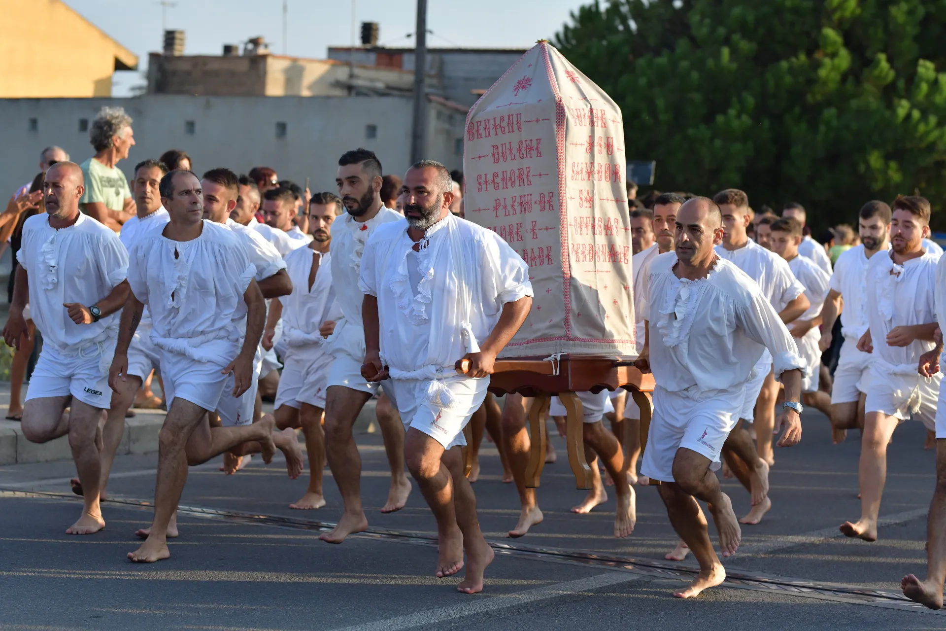 Uomini vestiti di bianco corrono durante la corsa degli scalzi di Cabras